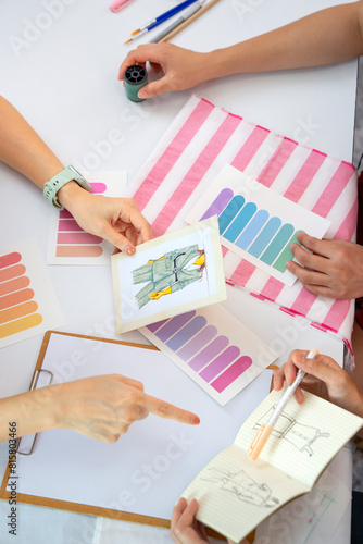 female fashion designer team discuss clothing design to woman customer with fashion sketch and color sample (selective focus), concept of clothing design,creativity,dressmaking,business and industry