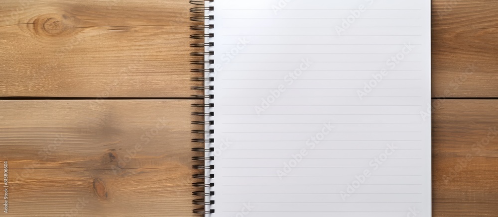 A spiral notepad placed on a wooden desk along with a pen offers a perfect copy space image A spiral notepad placed on a wooden desk along with a pen offers a perfect copy space image