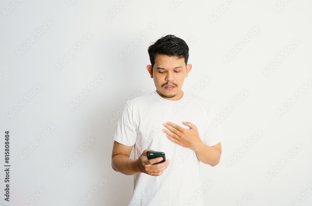 Asian man holding mobile phone and feeling shocked portrait white isolated Asian man holding mobile phone and feeling shocked portrait white isolated