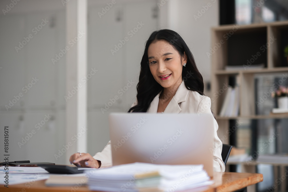 Asian businesswoman working on financial document with laptop on desk in office room Asian businesswoman working on financial document with laptop on desk in office room
