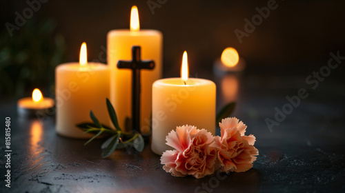 Candles with cross and carnation flower on dark background
