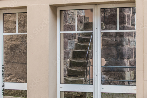 Mittelalterliche ausgetretene Steintreppe mit Handlauf aus Metall spiegelt sich in Fenster am Bickentor in Villingen.  photo