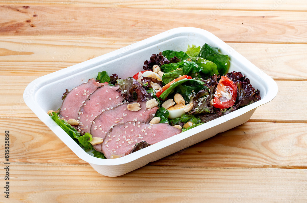 Salad with roast beef sous-vide. Healthy food. Takeaway food.  On a wooden background.