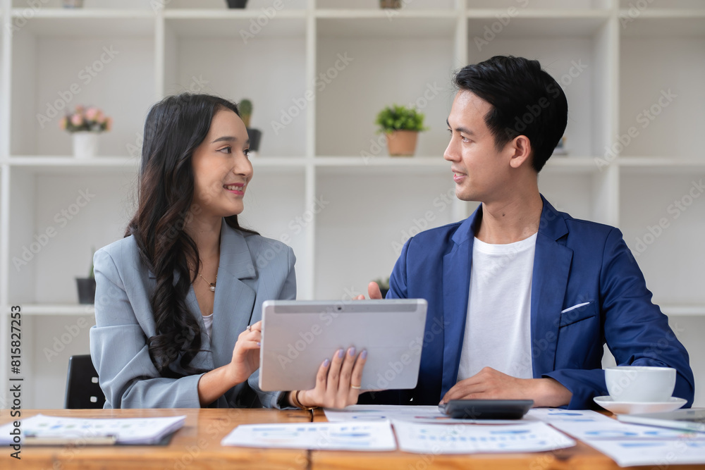 A young businessman and a female Asian accountant are discussing financial accounting and business planning together in the office. A young businessman and a female Asian accountant are discussing financial accounting and business planning together in the office.