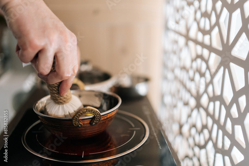 Εκτύπωση καμβά Close-up hands of unrecognizable ayurvedic massage practitioner dipping cotton-wrapped herbal bundle into aromatic oil during prepare to Shirodhara treatment
