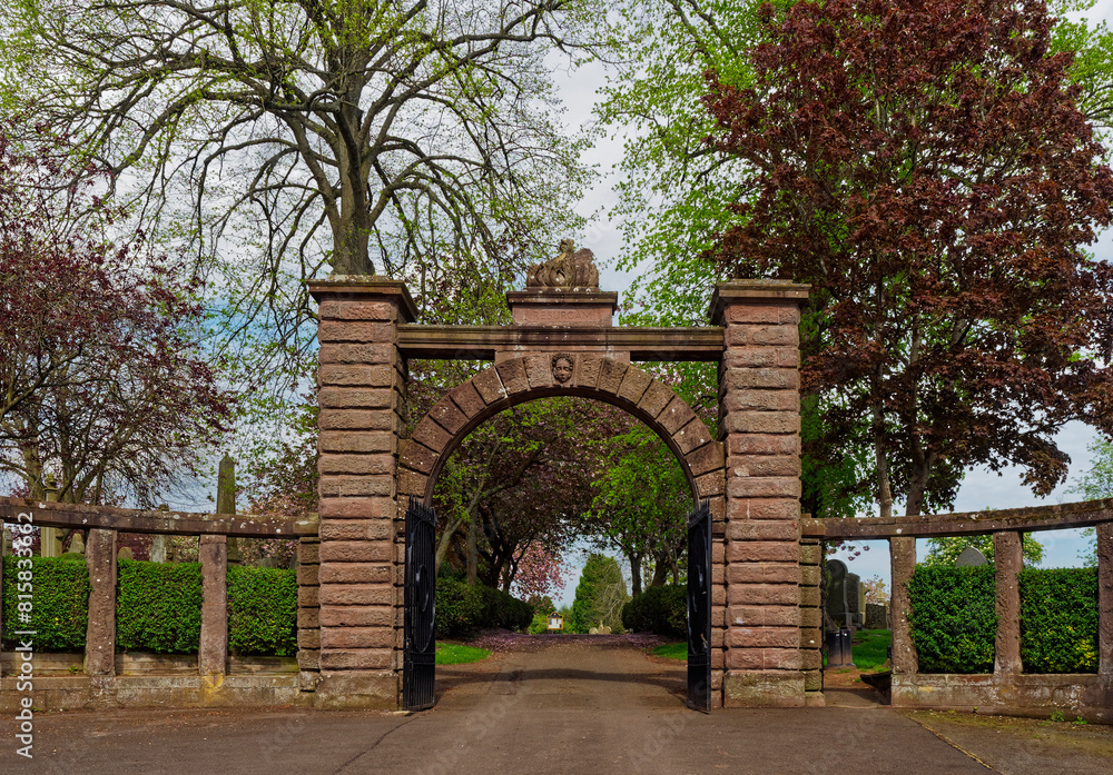 Obraz premium The Stone pillared semi circular Entrance to Brechin Cemetery, with its black cast Iron Gates open on a May afternoon.