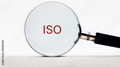 The concept of ISO quality control certification approval. Abbreviation ISO text appeared through a magnifying glass on a white background