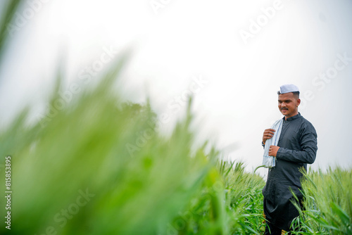 Young Indian farmer in a field of green wheat