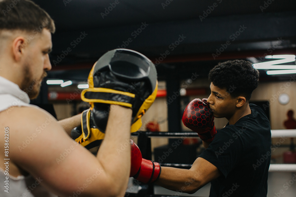 Afro American boxer in gloves is training with a coach in the boxing ring Afro American boxer in gloves is training with a coach in the boxing ring