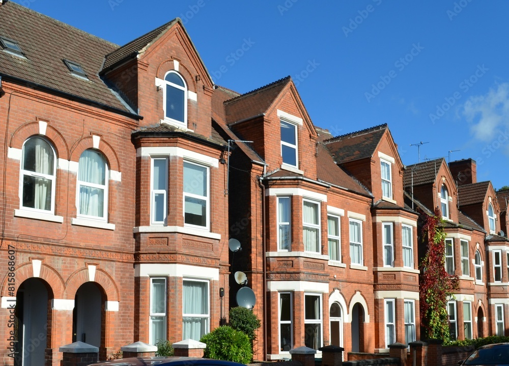 typical English small town street with narrow terraced, adjoining red brick houses with bay windows typical English small town street with narrow terraced, adjoining red brick houses with bay windows