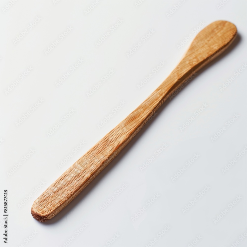 A wooden butter knife with a long handle, placed on the white table top A wooden butter knife with a long handle, placed on the white table top