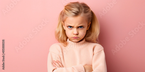 Little sad offended child with folded hands on a pink background, close-up portrait of a little girl, indoors, сopy space