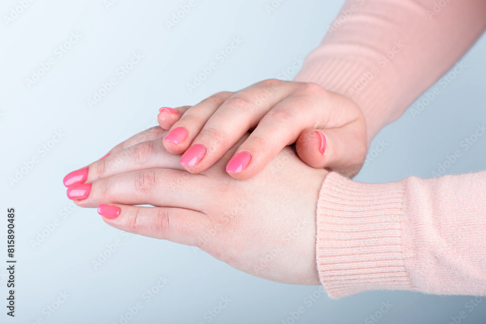 Pink stylish manicure on women's hands opposite blue background.. Pink stylish manicure on women's hands opposite blue background..