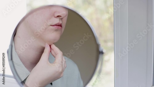 double chin in a caucasian woman. Woman pinching fat on chin and looking at mirror close up