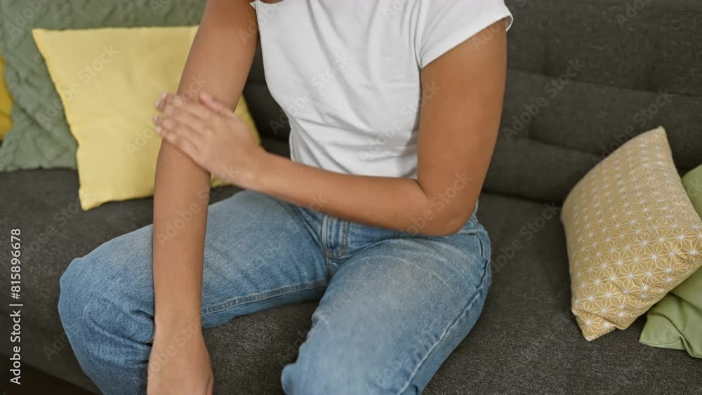 Casual woman scratching arm on sofa with colorful pillows in a modern apartment. Casual woman scratching arm on sofa with colorful pillows in a modern apartment.