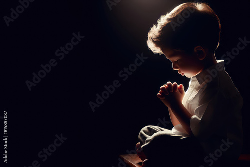 small boy praying  rim light Isolated on black background