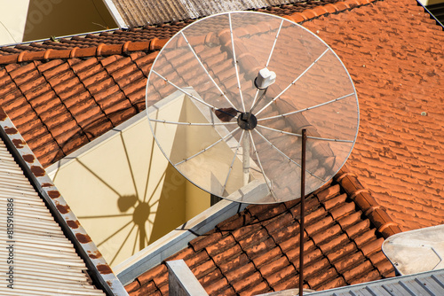 Satellite dish on the roof tile.Parabolic antenna  an antenna for catching domestic and foreign TV broadcasts  mounted on the roof of a building  in Brazil