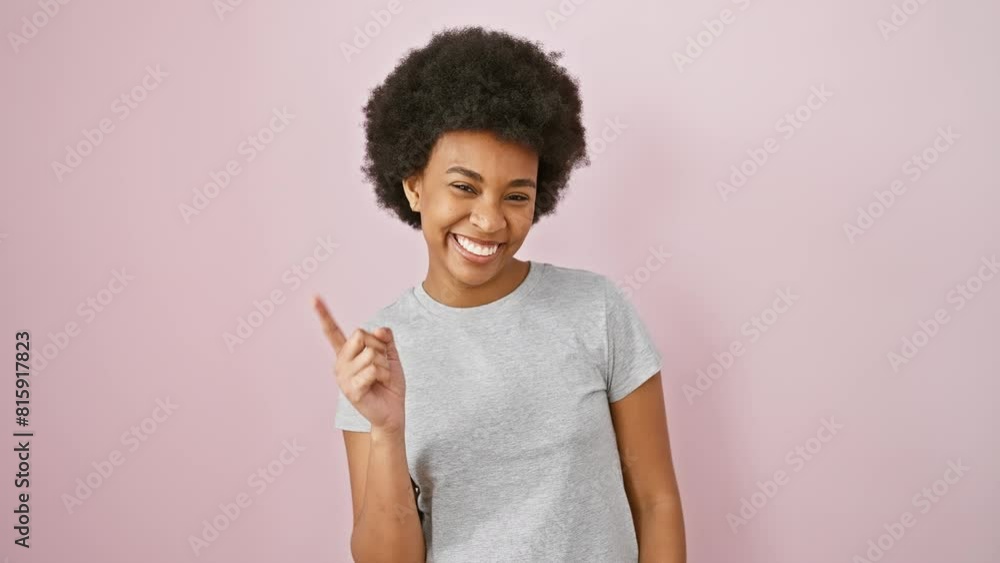 Cheerful african american woman in a t shirt, confidently pointing up - a glowing idea! standing against an isolated pink background with a radiant, happy face. number one at surprises! Cheerful african american woman in a t shirt, confidently pointing up - a glowing idea! standing against an isolated pink background with a radiant, happy face. number one at surprises!