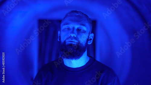 Portrait of a young stylish hipster man rapper moving and posing to the camera. Media. Neon lighting background creating effect of spinning tunnel.