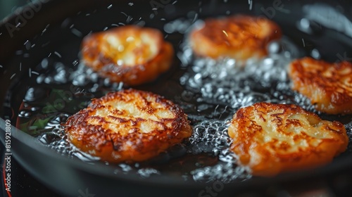 Close-up on potato pancakes frying to perfection, the golden-brown texture crisply captured against the speckled surface of the pan photo