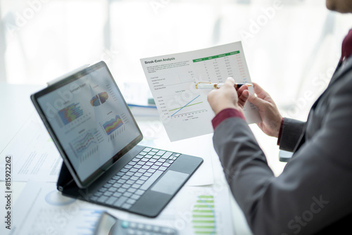 A man is looking at a computer screen with a piece of paper in front of him