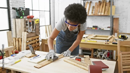 A focused woman sands wood in a well-equipped carpentry workshop, showcasing her skill and dedication to the craft.