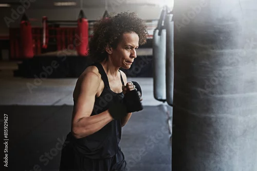 Obraz Fitness, punching bag and mature woman in boxing ring for workout, challenge or competition training. Power, muscle and champion boxer in exercise with confidence, fight and energy in MMA sports club
