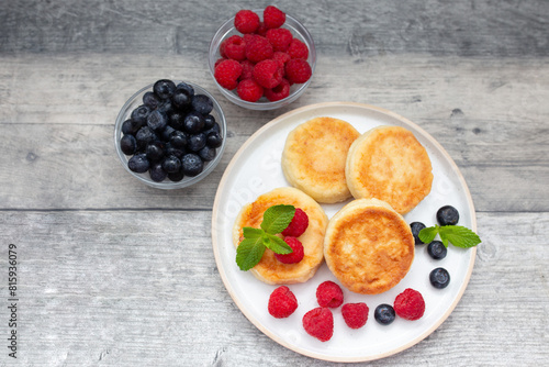 Cottage cheese pancake or syrniki with fresh raspberries and blueberry on dark wooden table.  Sweet breakfast or lunch, tasty dessert. 