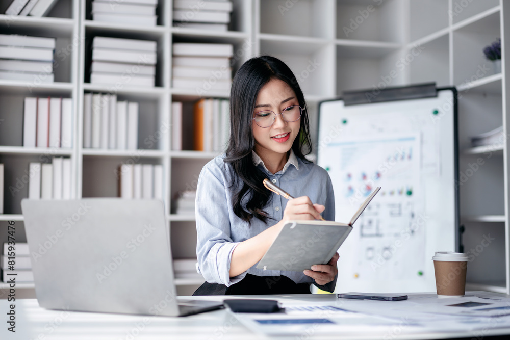 Accounting business concept, Accountant woman reading finance chart on laptop with paperwork and writing Accounting business concept, Accountant woman reading finance chart on laptop with paperwork and writing