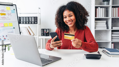 A woman is smiling while using her cell phone to pay for something