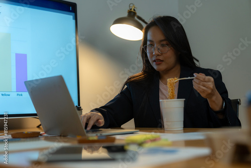 The woman ate instant noodles while working late at the office. photo