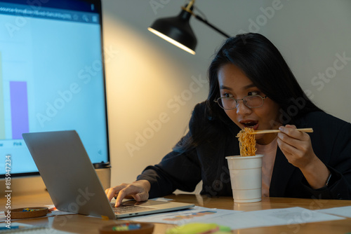 The woman ate instant noodles while working late at the office. photo
