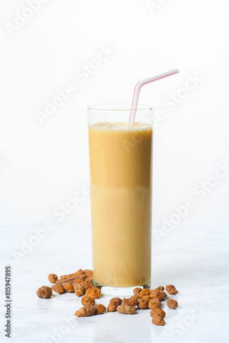 Glass of horchata smoothie with chirimolla on marble table with tiger nuts...