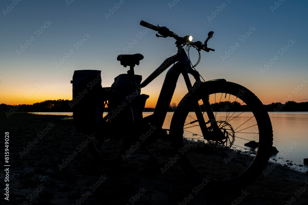 Fototapeta premium Silhouette of electric bicycle on beach of pond Bezdrev after sunset