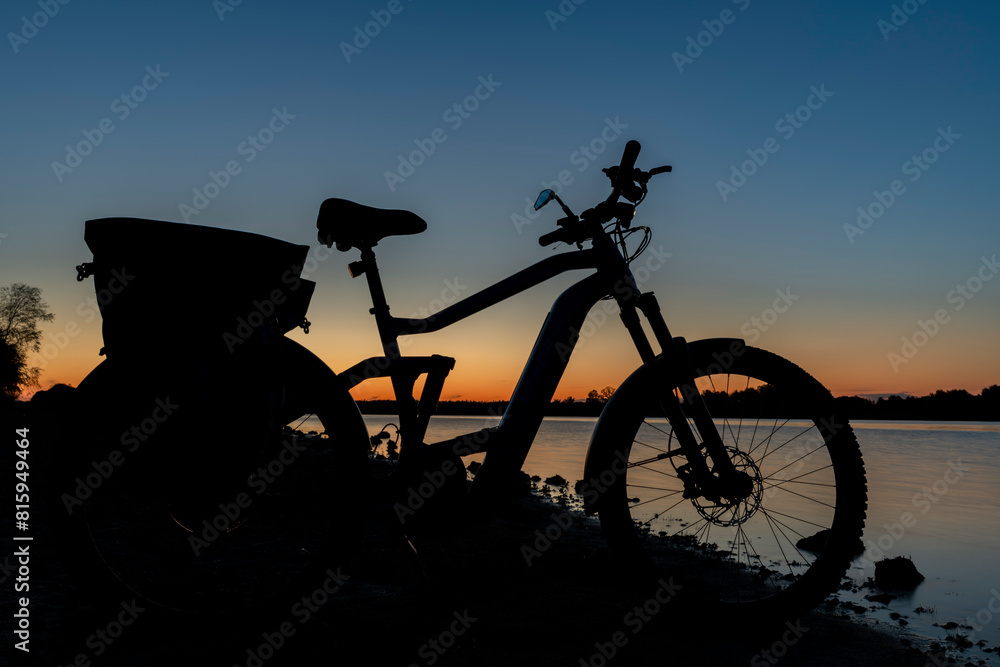 Silhouette of electric bicycle on beach of pond Bezdrev after sunset Silhouette of electric bicycle on beach of pond Bezdrev after sunset