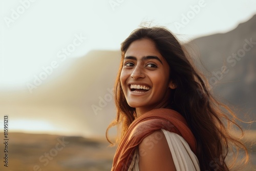 portrait of a beautiful indian woman outside, glancing over her shoulder and laughing photo