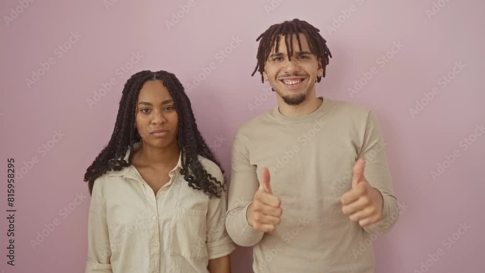 A couple expresses contrasting emotions, a man thumbs-up and a woman thumbs-down against a pink wall, depicting diverse reactions. A couple expresses contrasting emotions, a man thumbs-up and a woman thumbs-down against a pink wall, depicting diverse reactions.