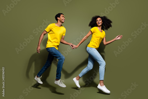 Full body portrait of two nice people hold arms run jump wear t-shirt isolated on khaki color background © deagreez