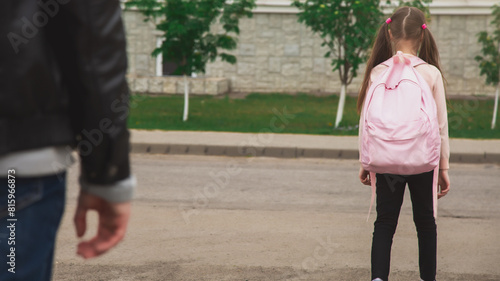 Father with cute little daughter see off to school elementary class outdoor near school building. Child pupil with backpack going dad with love before going classroom