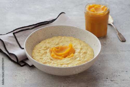 Bowl of oatmeal with pumpkin on a gray textured background. Delicious healthy homemade breakfast photo