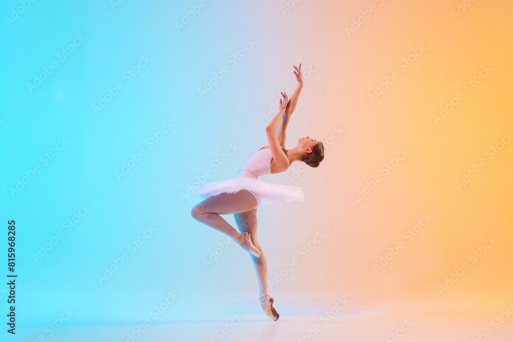 Young ballerina in white tutu dancing and leaning backwards in motion in neon light against blue-orange gradient background. Concept of art, movement, classical and modern fusion, beauty and fashion.