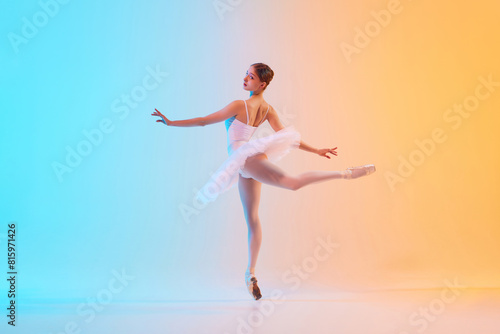 Young ballerina in white tutu doing arabesque in motion in neon light against blue-orange gradient background. Concept of art  movement  grace  classical and modern fusion  beauty and fashion. Ad