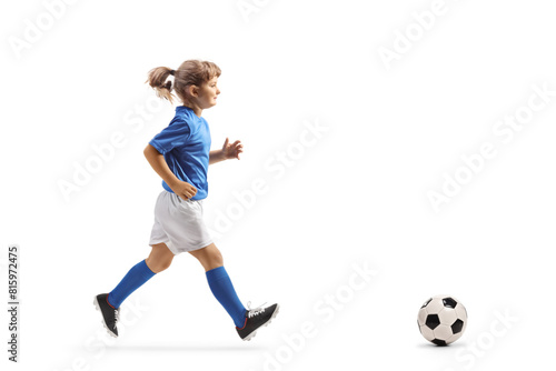 Full length profile shot of a girl in a football jersey running after a ball