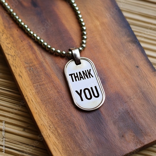 label with chain.a military dog tag placed on a wooden background, bearing the inscription "thank you". Pay attention to the texture of the wood and the engraved details on the dog tag, evoking a sens