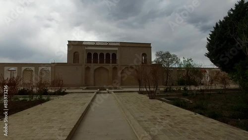 footage of an ancient persian villa, showing the green courtyard and the mansion from a close view. photo