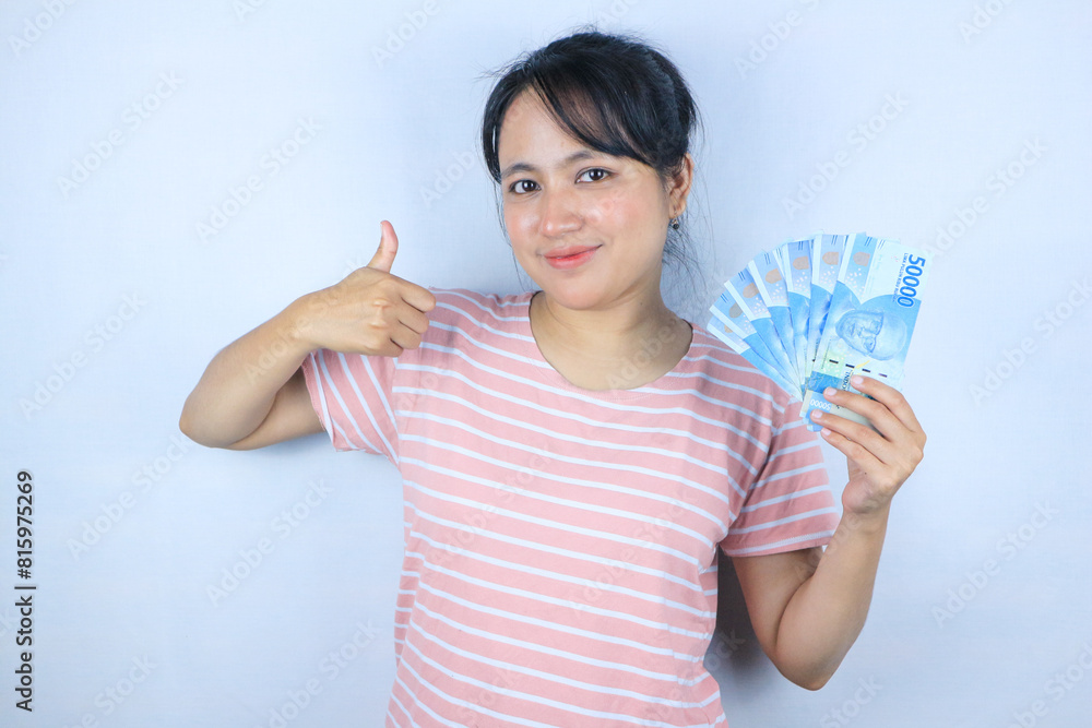 Portrait of a young Asian woman holding cash while giving a thumbs up. Advertising concept Portrait of a young Asian woman holding cash while giving a thumbs up. Advertising concept
