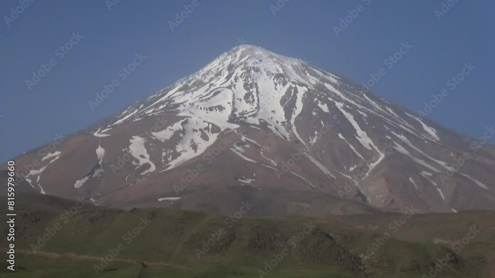 majestic Damavand mountain, showing a light dusting of snow as a flock of sheep peacefully graze on the lush plain. majestic Damavand mountain, showing a light dusting of snow as a flock of sheep peacefully graze on the lush plain.