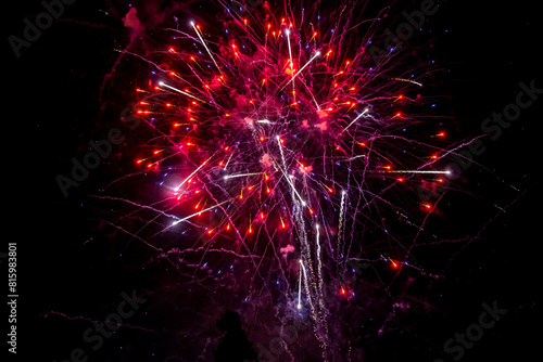 Pink fireworks explode in the night sky. Selective focus.