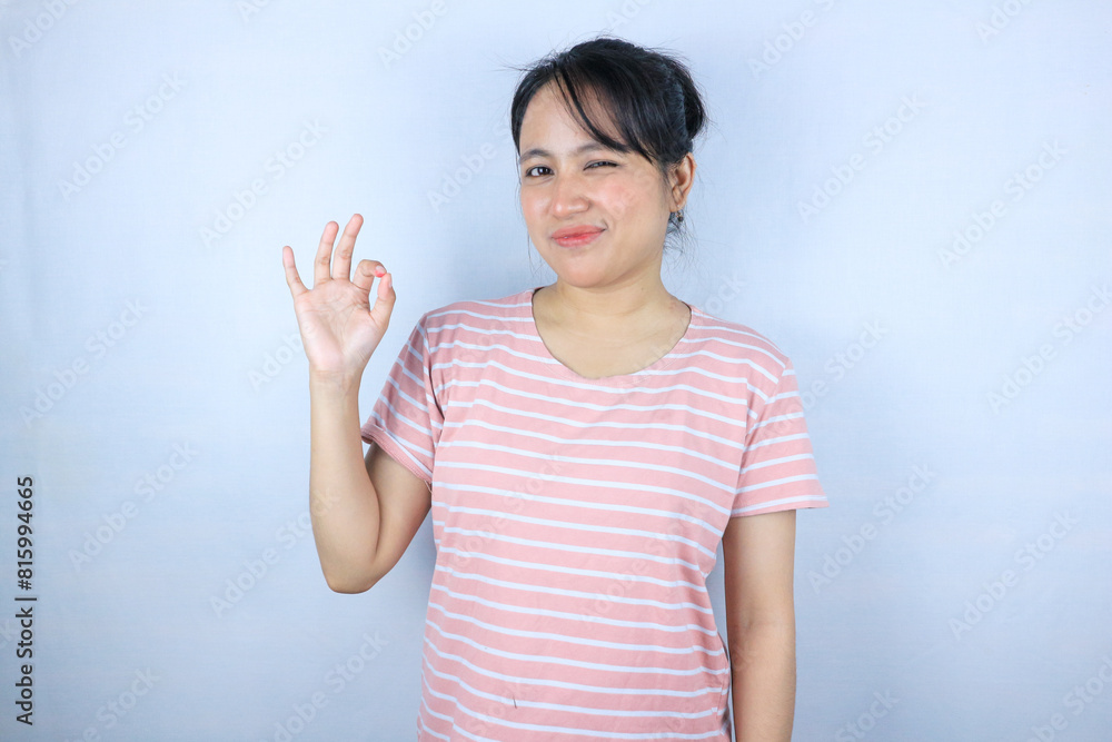 Smiling young Asian woman shows okay sign on white background. Smiling young Asian woman shows okay sign on white background.
