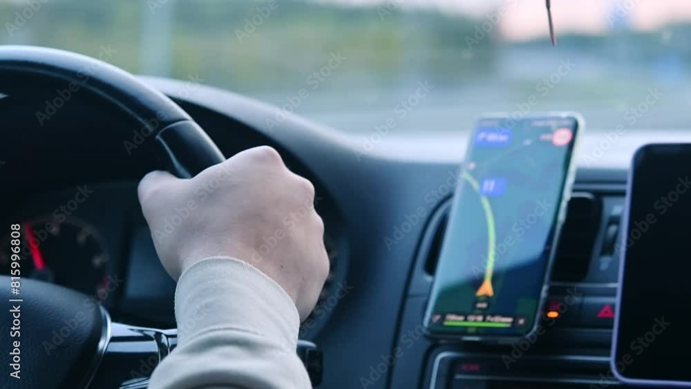 Person drives a car with a cell phone with a navigator on the dashboard. Person drives a car with a cell phone with a navigator on the dashboard.